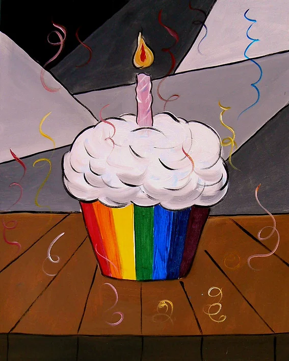 Birthday cupcake with rainbow base and white frosting, single lit candle, confetti.