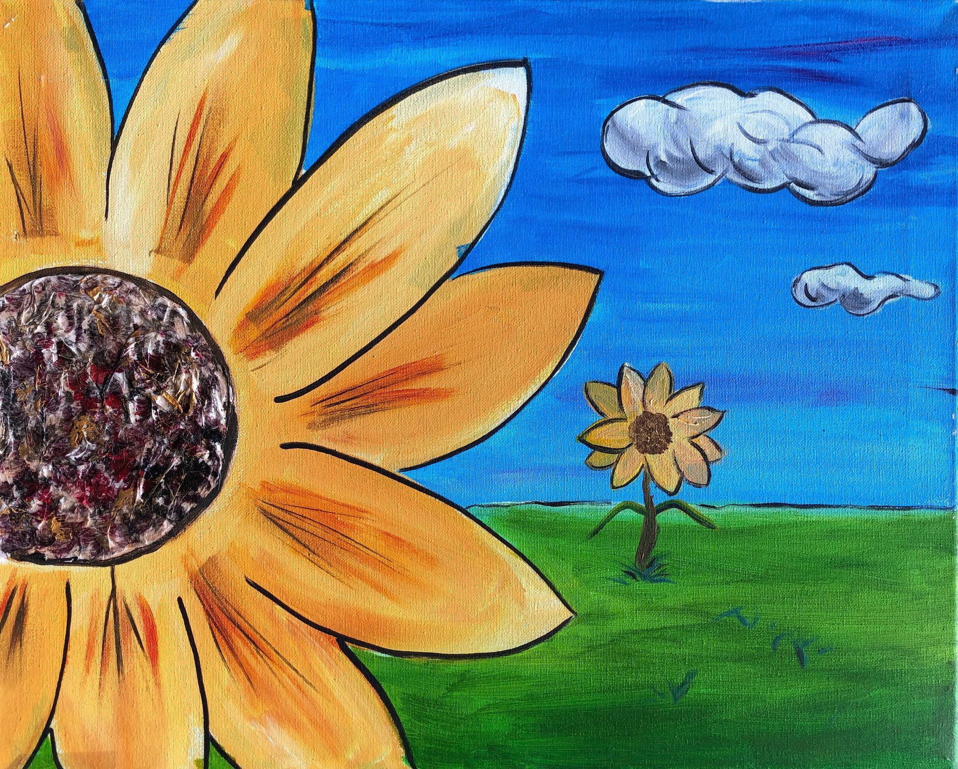 A large sunflower in the foreground with a smaller one in a green field under a blue sky with clouds.
