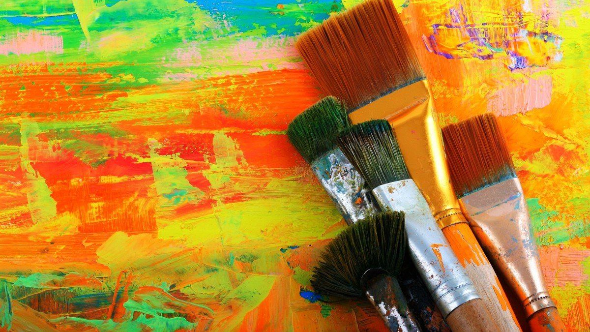 Paintbrushes with paint on a colorful abstract painting.