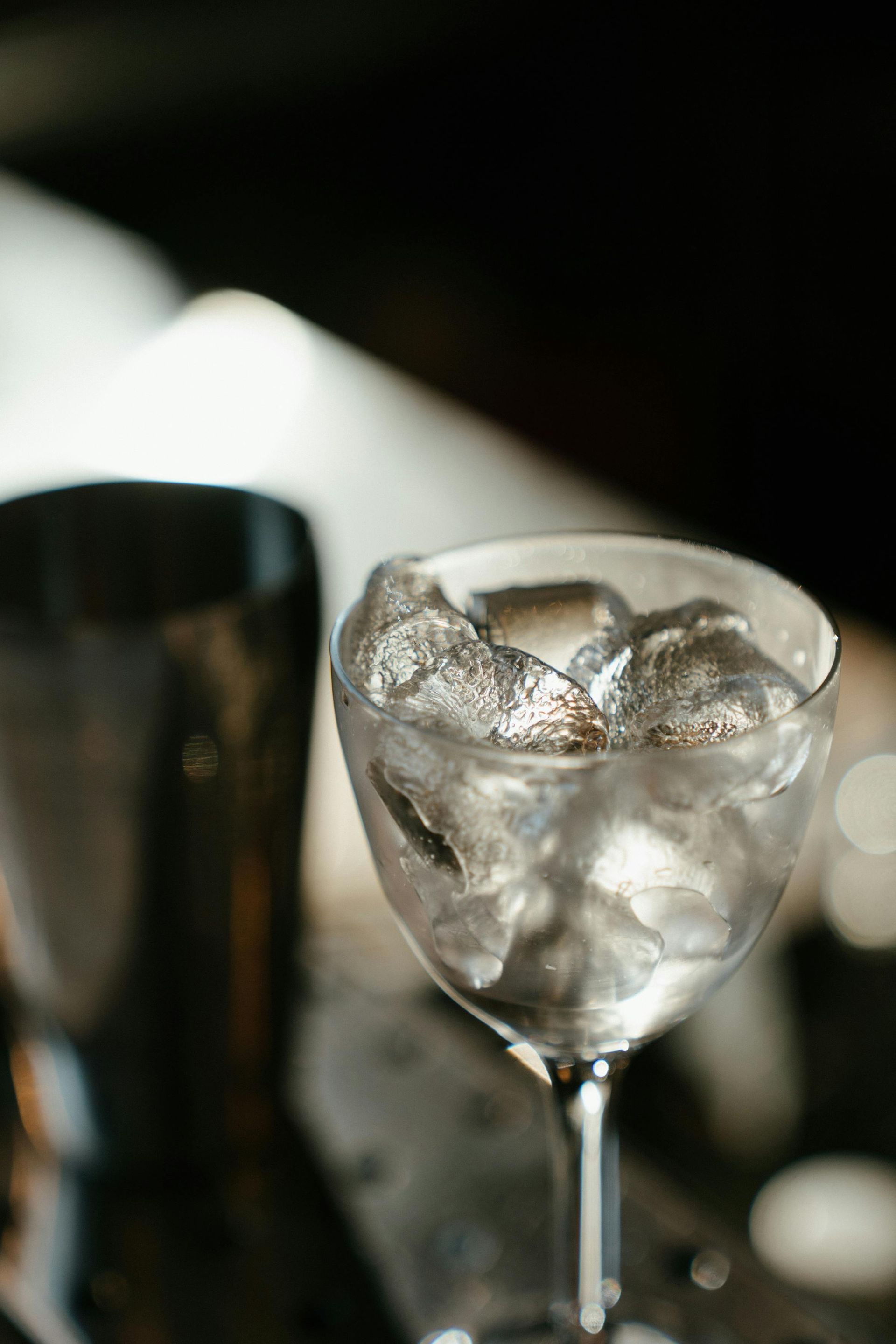 A martini glass filled with ice cubes on a table.