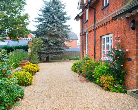 a brick house with a gravel driveway leading to it