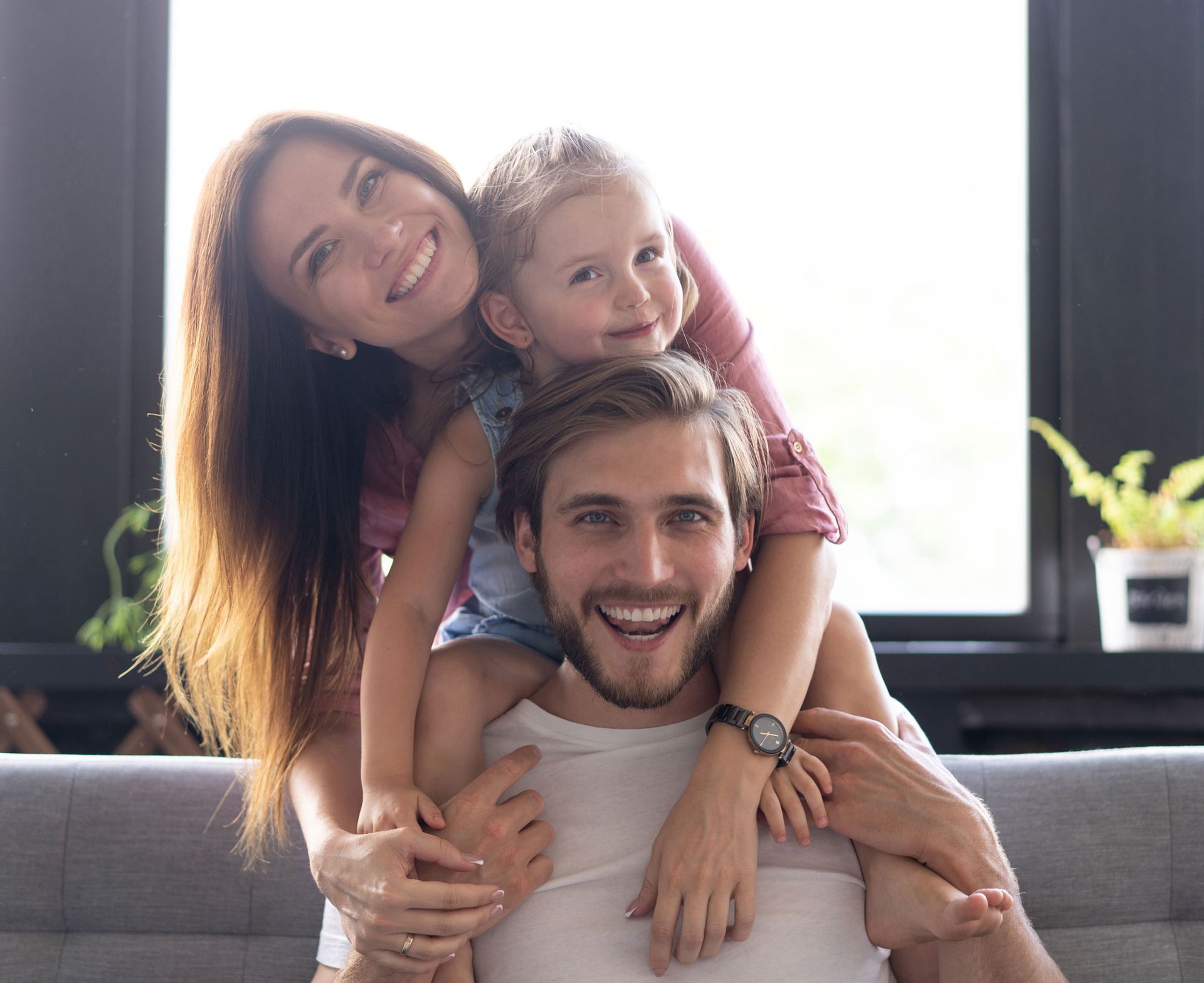 A family is sitting on a couch holding a drawing of their family.