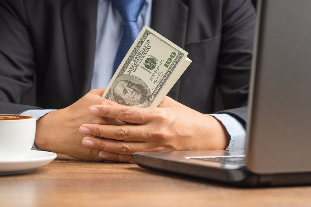 A man in a suit and tie is holding a stack of money in his hands.