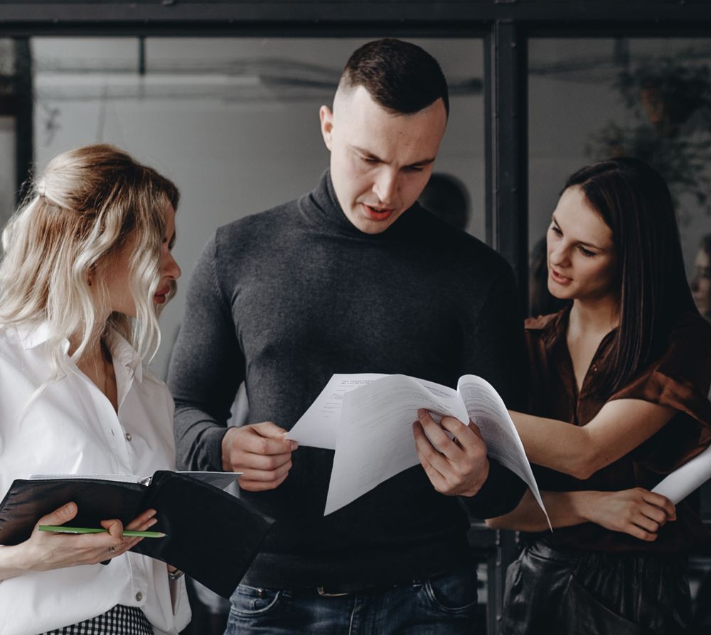 A man and two women are looking at a piece of paper.