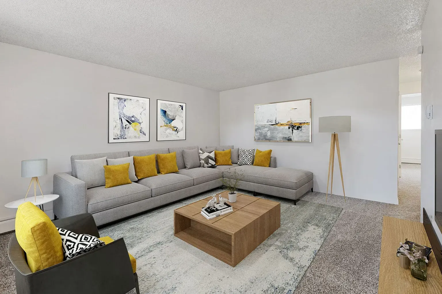 A modern living room with a large gray sectional sofa, yellow accents, a wooden coffee table, and abstract wall art.