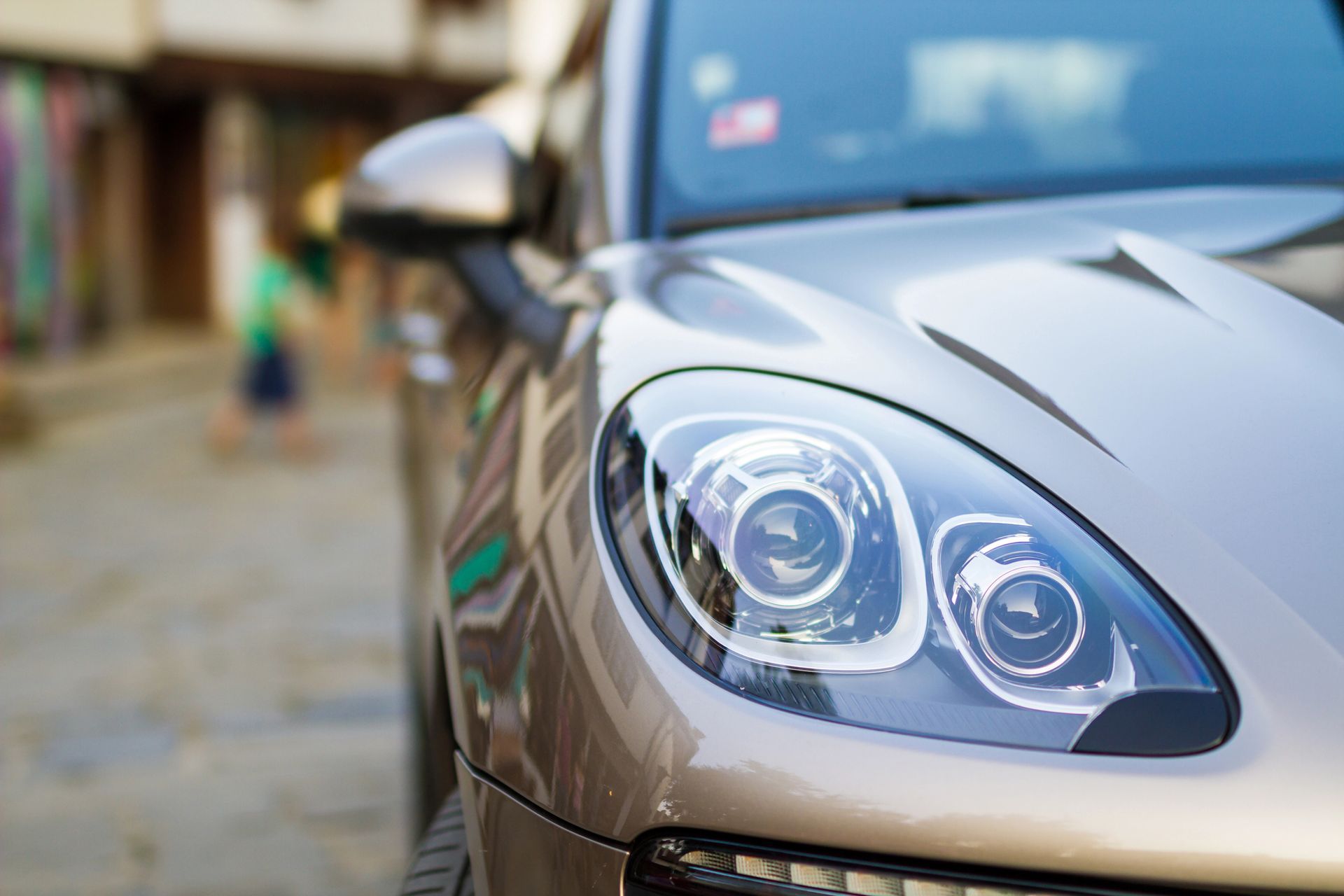 Primo piano del faro marrone di un'auto. L'auto si trova su una strada acciottolata con sfondo sfocato.