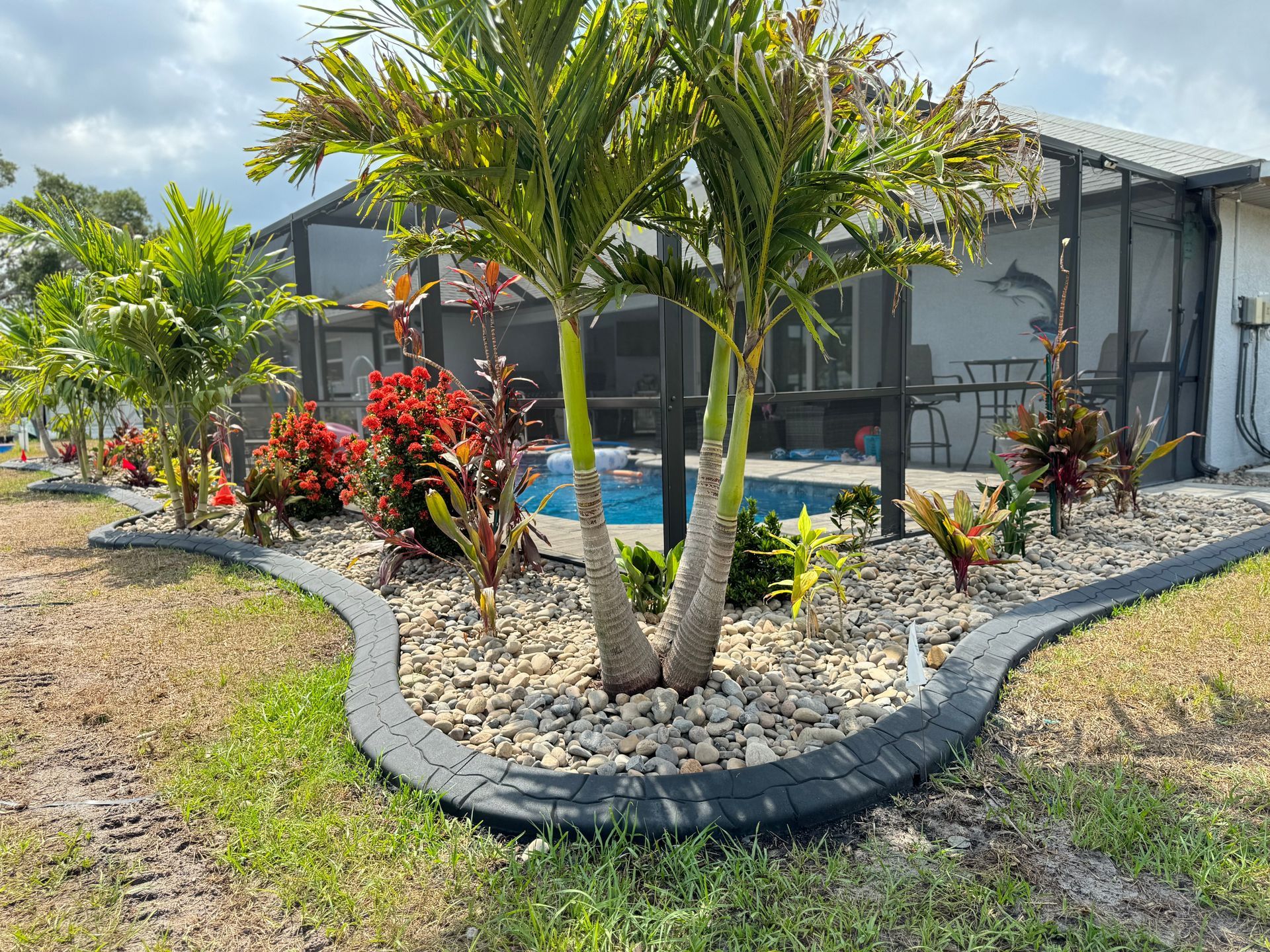 A garden with plants and mulch in front of a house.
