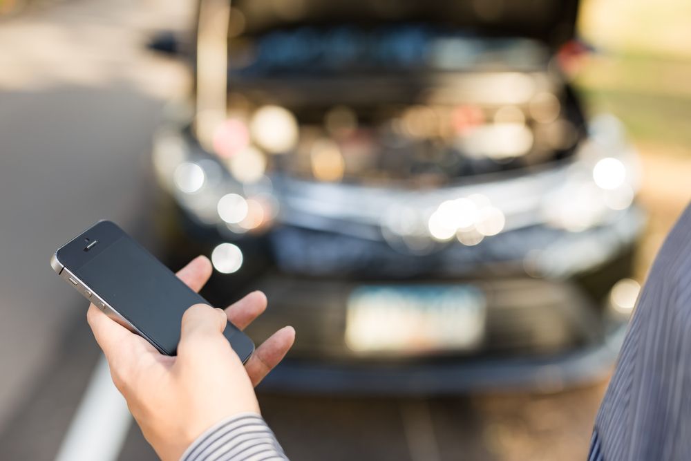 Person Holding a Phone Near a Car With the Hood Open — JDM Mobile Mechanical in Campbelltown, NSW