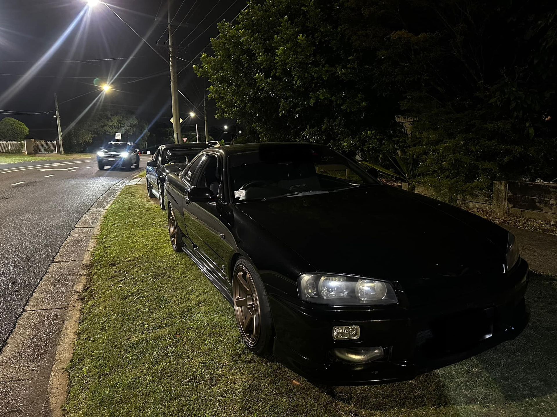 Black car parked on a grassy verge at night, other cars on the road. — JDM Mobile Mechanical in Fairfield, NSW