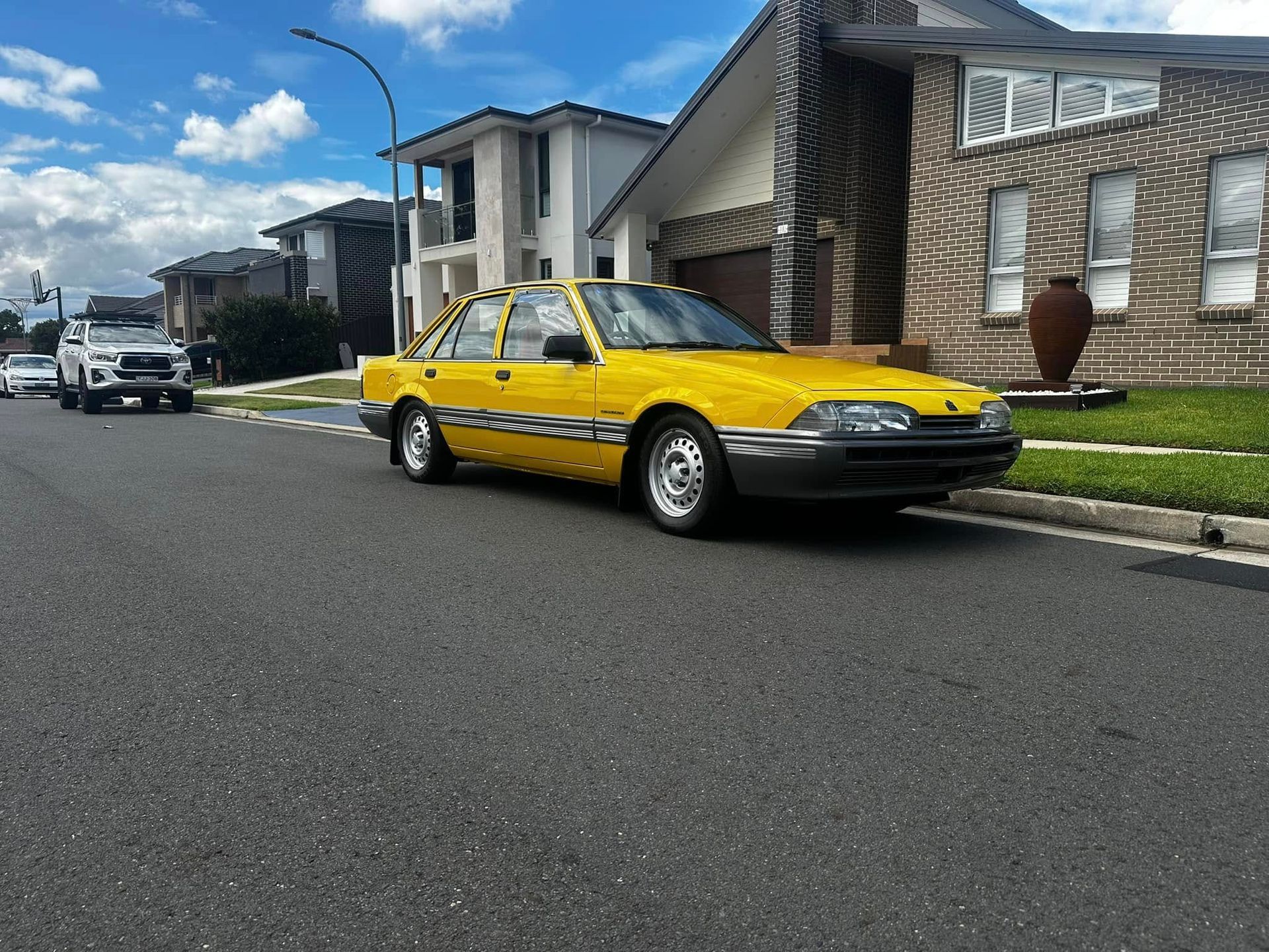 Yellow sedan parked on a suburban street with houses and a vehicle in the background. — JDM Mobile Mechanical in Holsworthy, NSW