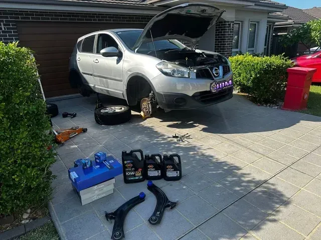 Car being worked on in driveway; hood open, wheels off. Tools, oil, and parts are laid out. — JDM Mobile Mechanical in Campbelltown, NSW