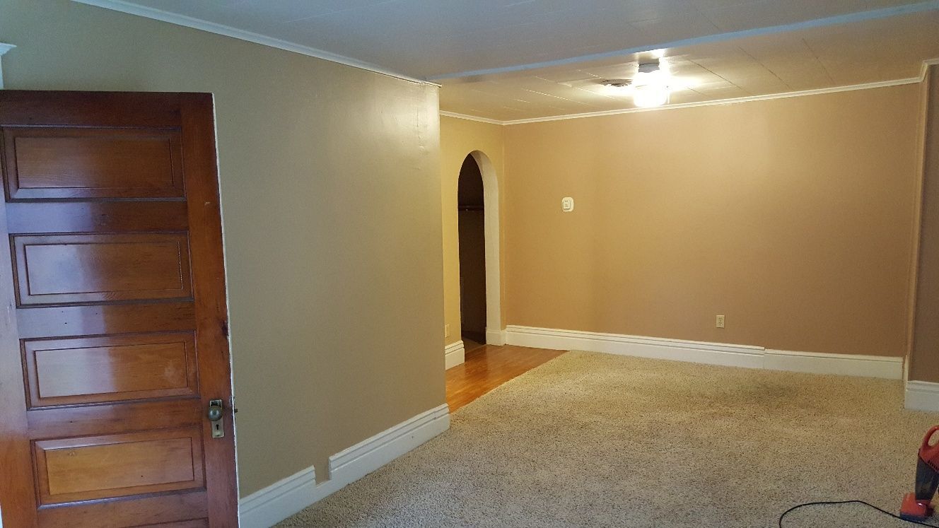 Interior room with beige walls, white trim, wood door, and carpet.