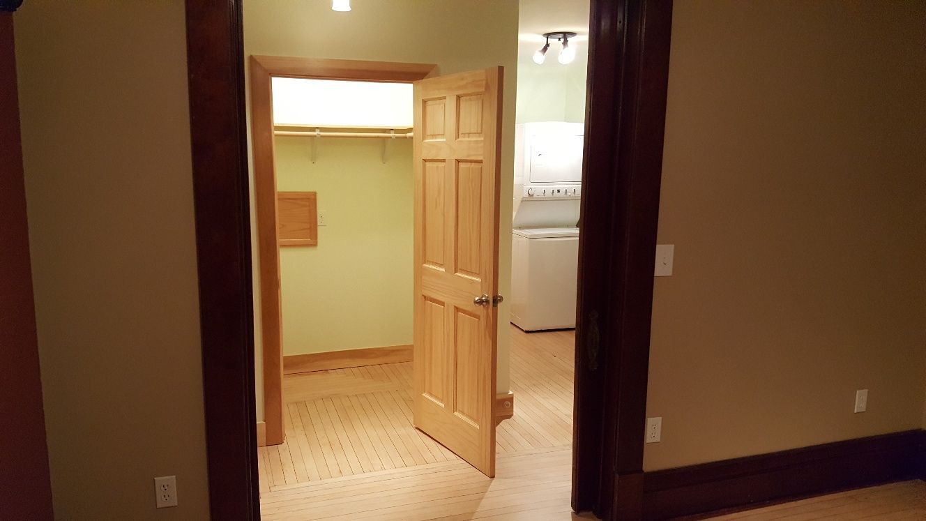 An open doorway revealing a closet, door, and a glimpse of a laundry room.