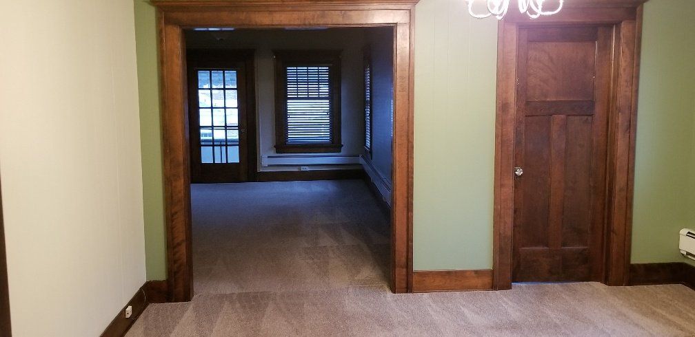 Interior view of rooms with wooden trim and doors, pale green and white walls, and a chandelier.
