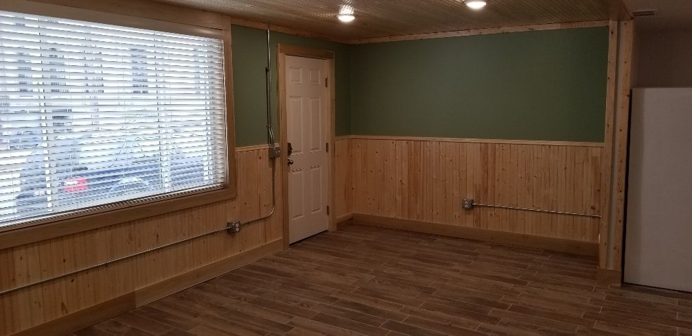 Interior of a room with wooden paneling, a green wall, a door, and a window with blinds.