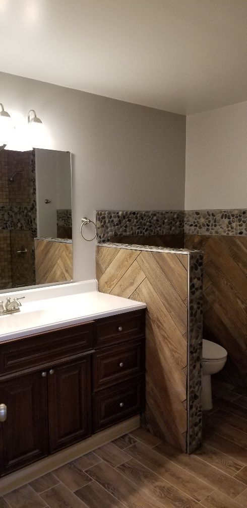 Bathroom with dark wood vanity, white countertop, herringbone wood-look tile, and a mosaic tile accent.