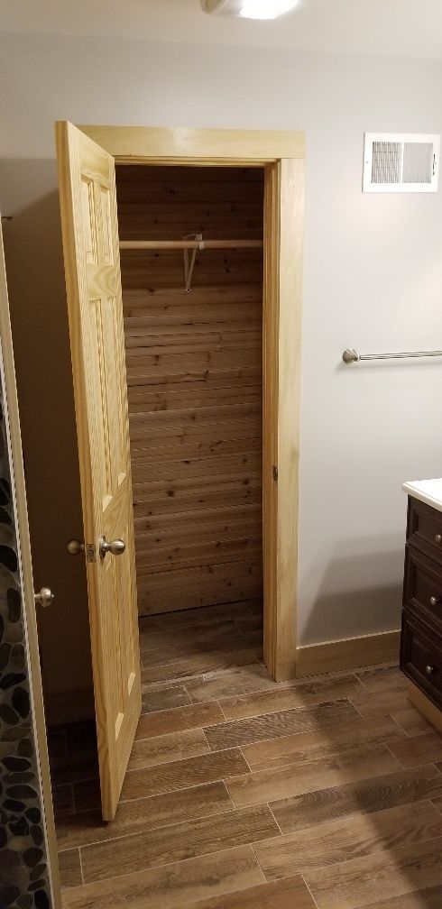Bathroom with open closet door and wood-look tile. Beige walls and trim.