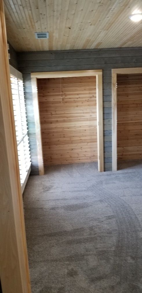Interior with wood paneling on the ceiling, walls, and doorways, with gray carpeting.