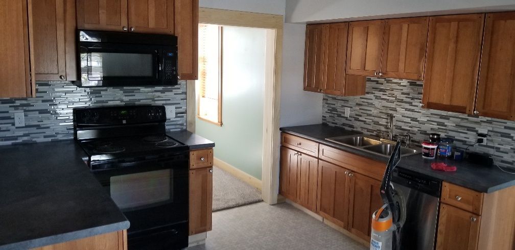 Kitchen with wooden cabinets, black appliances, and a mosaic tile backsplash.