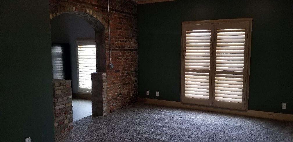 Interior with archway and brick wall, dark green walls, and shuttered windows.