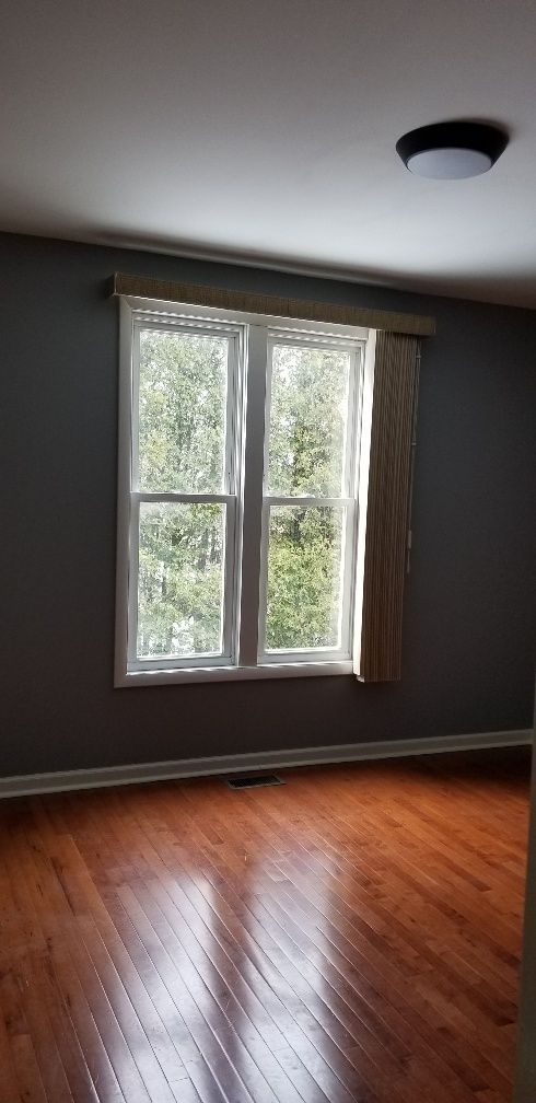 Room with a window, hardwood floor, and a dark ceiling with a circular light. The walls are gray.