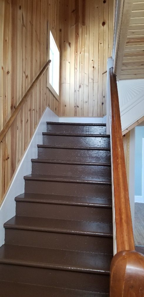 Wooden staircase with brown steps and handrails, natural wood walls, and a small window.
