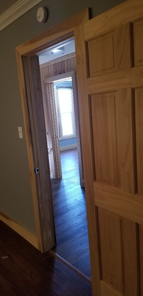 Interior hallway with light wood doors, and dark wood floors.