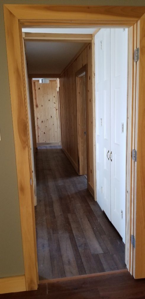 Hallway with wood paneling, dark wood-look flooring, and a white-paneled door.
