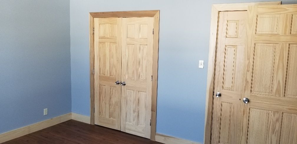 Room with blue walls, wood doors and trim, and hardwood floor.