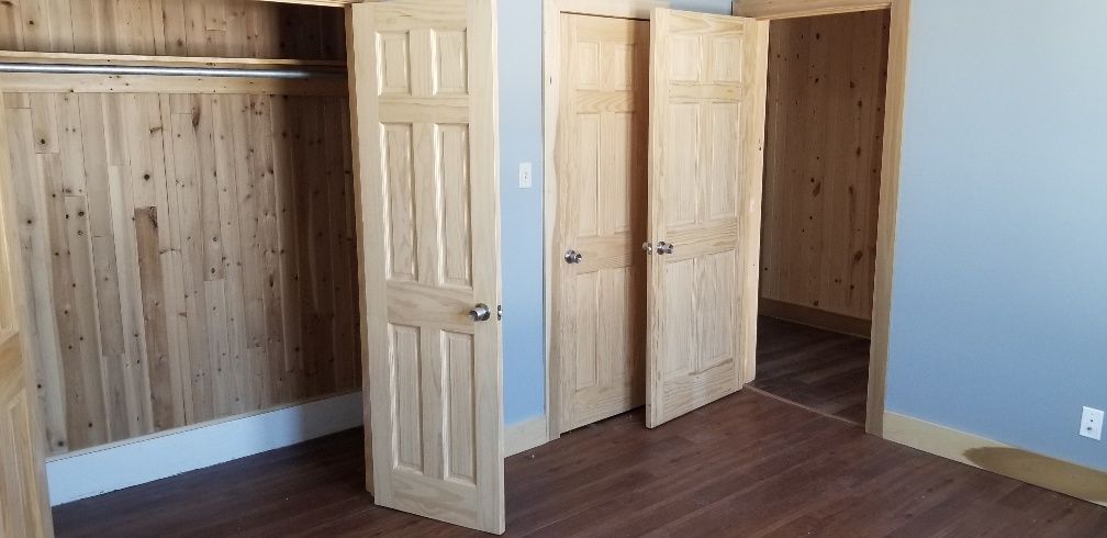 Bedroom closet with wooden paneling, doors, and a rod for hanging clothes.