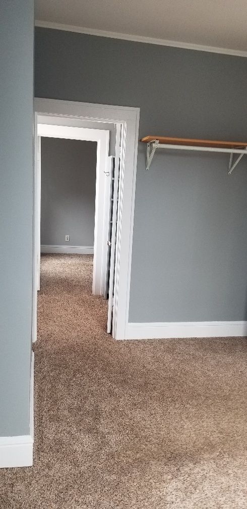 Interior view of a room with gray walls and carpet. An open doorway leads to other rooms.