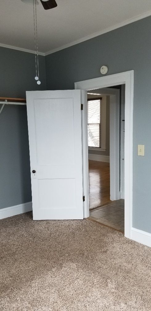 An interior shot of a room with gray walls, white trim, and a partially open white door.