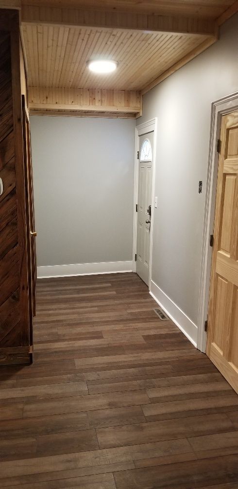 Hallway with wood floors, light gray walls, and a wood ceiling with a circular light.