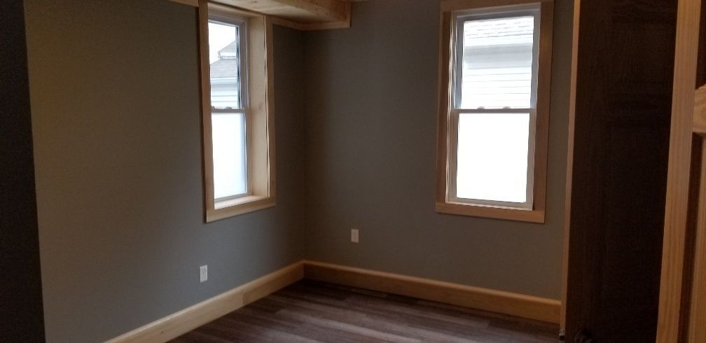 Interior view of a room with two windows, wood trim, dark walls, and dark flooring.