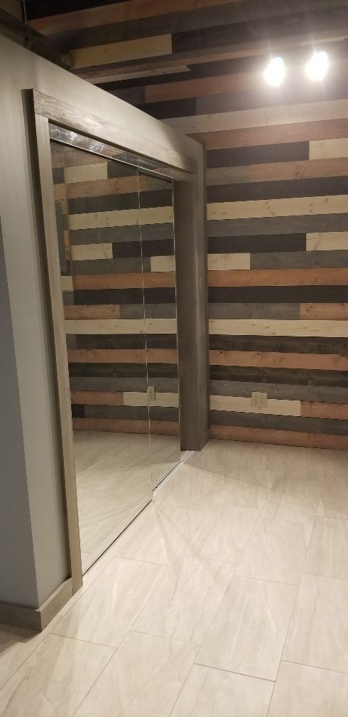 Interior view of a room with a wooden accent wall and light-colored tiled floor, mirror door.