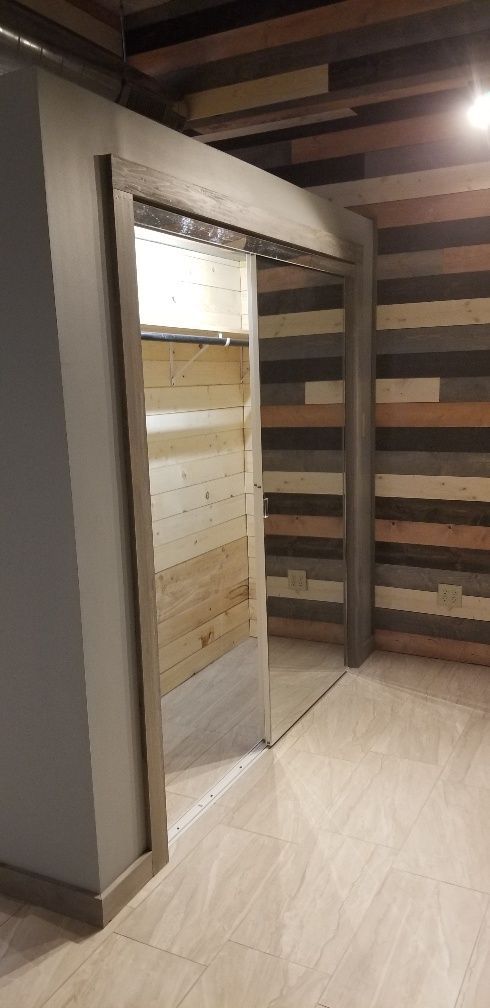 Sliding door with wood paneling, light colored flooring, and a neutral-colored wall.