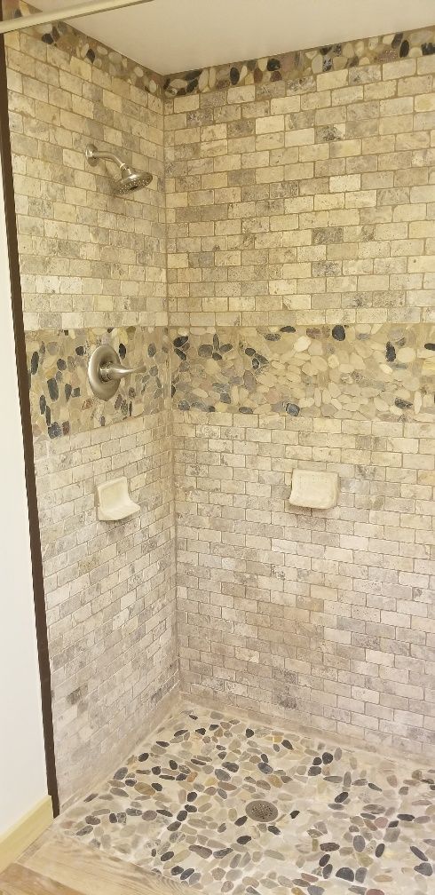 Shower stall with stone tile walls and pebble floor.