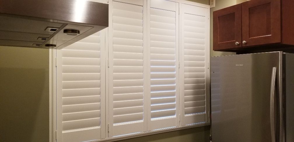 Kitchen interior with white shutters, stainless steel appliances, and dark wooden cabinets.