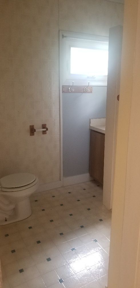 Bathroom with toilet, sink, window, and patterned floor.