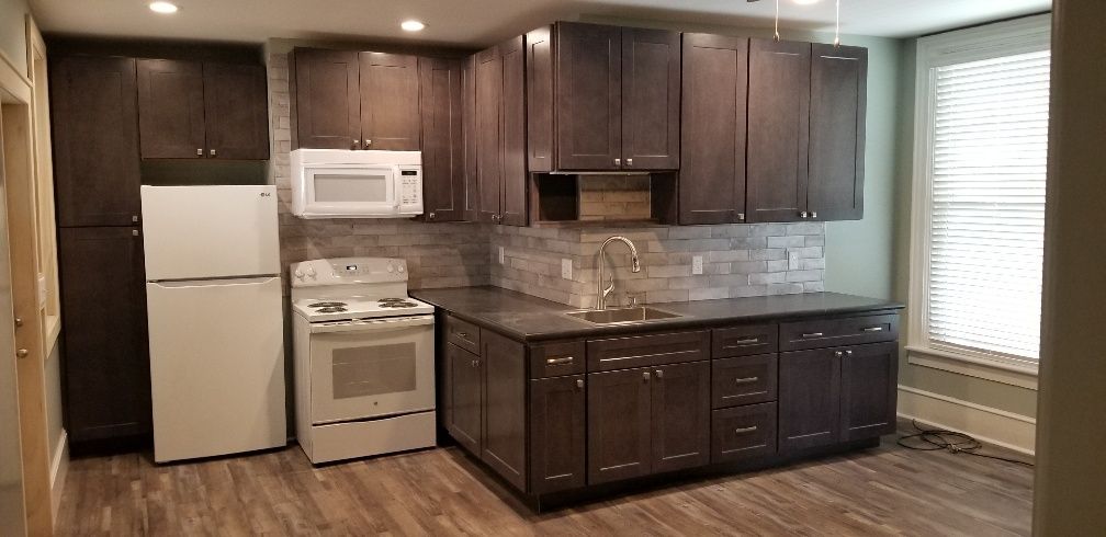 Kitchen with dark brown cabinets, white appliances, and gray-tiled backsplash.