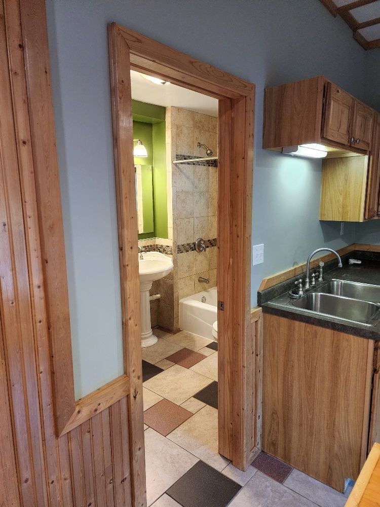 Bathroom doorway with wood trim, opening to a bathroom with tiled floor and green wall.