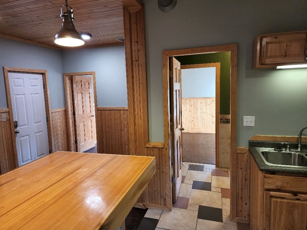 Interior view of a kitchen with wood paneling, countertops, and doorways leading to other rooms.
