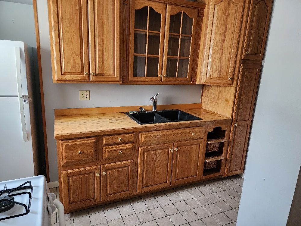 Oak kitchen cabinets with a black sink. A refrigerator and stove are partially visible.