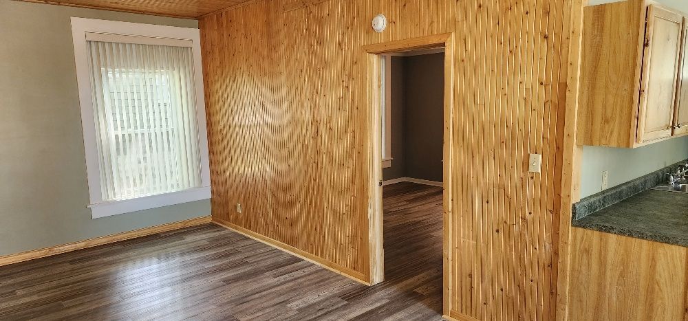 Interior view of a room with wood paneling, a window, and a doorway.