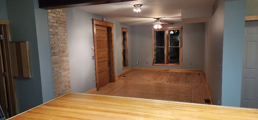 Interior of a house with light wood flooring, blue walls, a wooden door, and a stone accent wall.