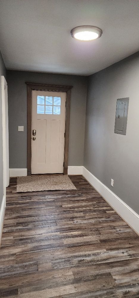 Hallway with a wooden floor, gray walls, white door, and a round ceiling light.