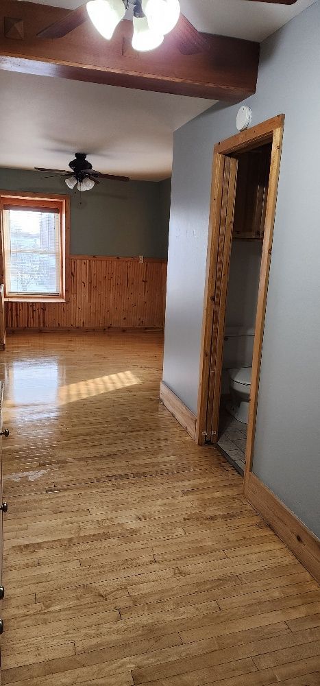 Interior view of a room with wooden floors, gray walls, and a visible doorway to a bathroom.