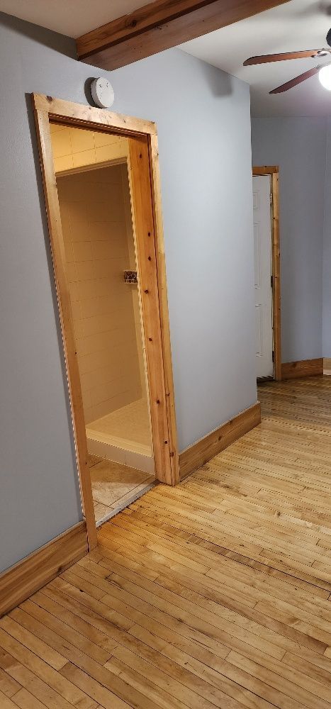 Wooden doorway leads to a small interior space, blue walls, wooden floors.