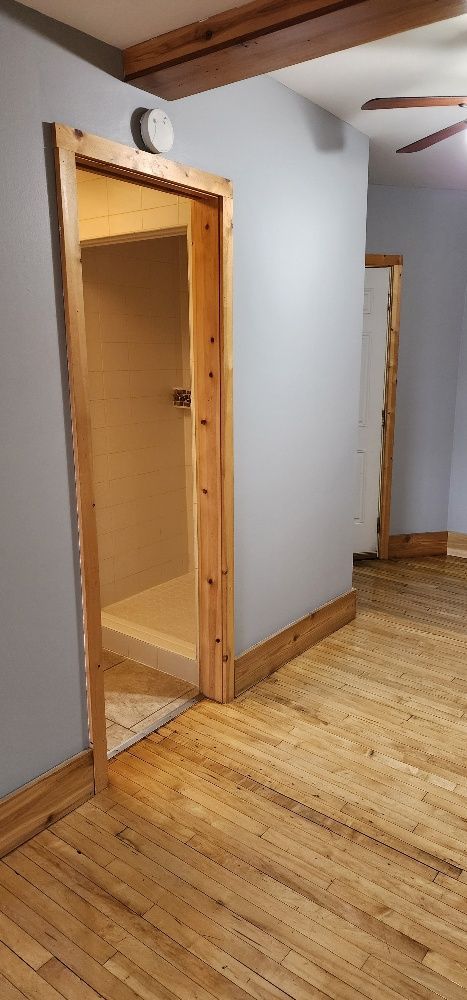 Interior view of a room with hardwood floors and a door frame leading to another room.