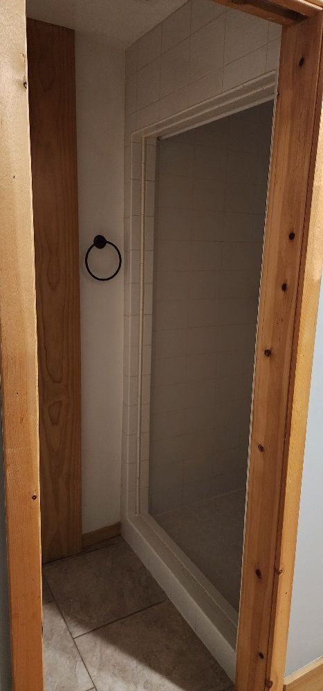 Bathroom doorway with brown wooden frame, towel ring, and tiled floor.